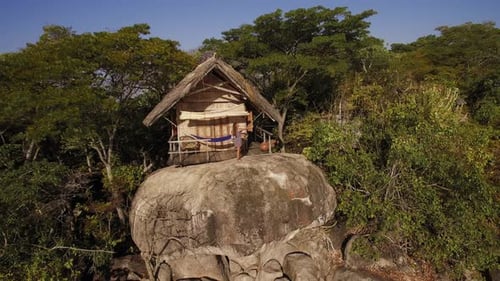 Woman stands by hut overlooking tropical island