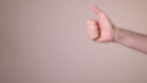Man showing thumbs down on beige background, closeup