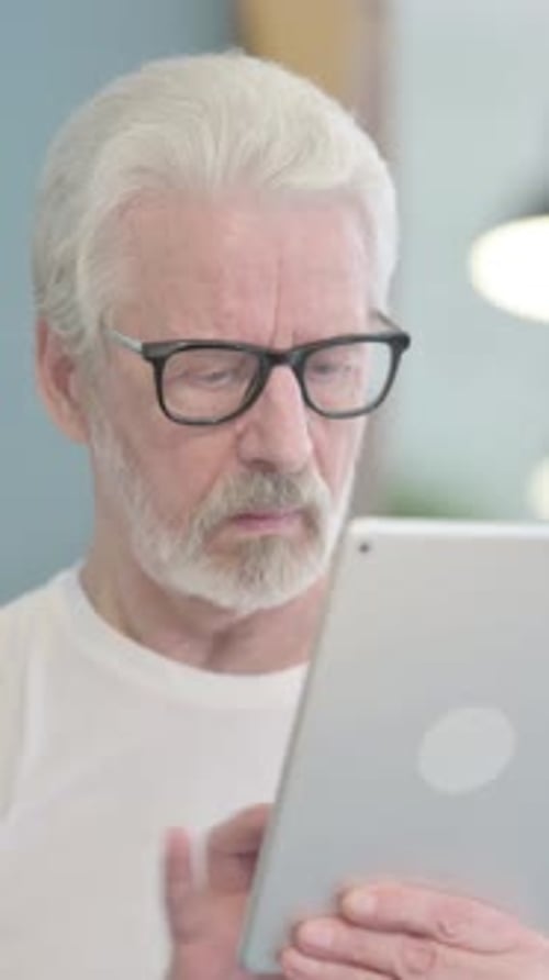 Portrait of Old Man Working on Digital Tablet, vertical video