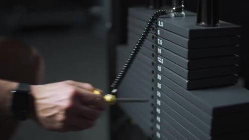 Anonymer Athlet Ein junger Sportler wählt das Gewicht auf dem Fitnessgerät und nimmt Gewichtheben in