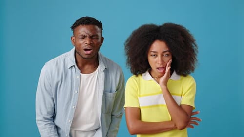 Schockiert über Neuigkeiten: Afroamerikanisches Paar auf blauem Hintergrund