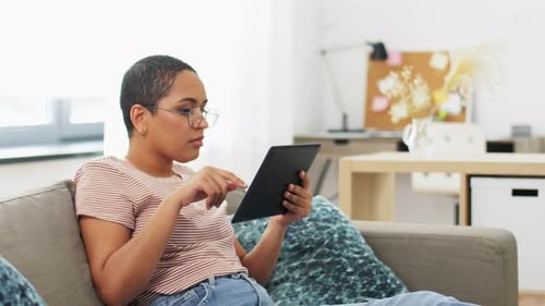 Woman Relaxing on Sofa Using Tablet at Home