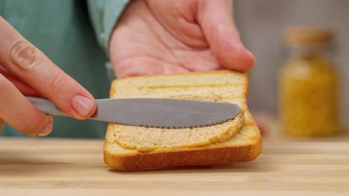 Femme étalant du pâté sur du pain dans la cuisine en gros plan