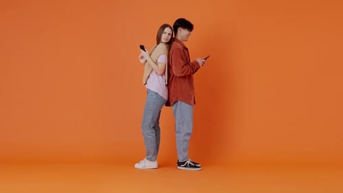 Young Adults Using Phones Back to Back in Studio