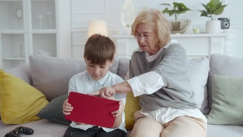 Boy and Senior Woman Using Tablet on Sofa