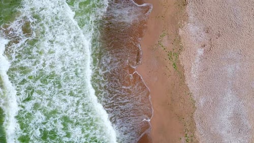 Aerial View of Ocean Waves Crashing Onto a Sandy Beach Creating a Beautiful Contrast Between the