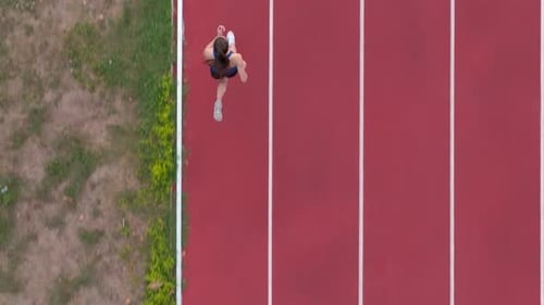 Top Down View Aerial Drone Shot of a Professional Female Athlete Sprinting on a Large Stadium