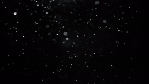 Schneefall vor schwarzem Hintergrund, der seitlich nach links fällt