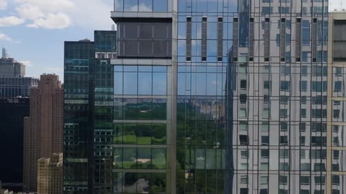 AERIAL: Central park reflecting from high-rise in sunny Midtown, Manhattan, NYC