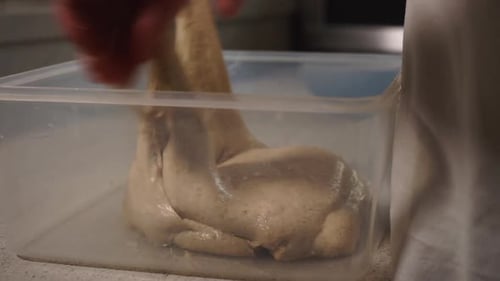 Young Male Chef forming sourdough and kneading and placing back into a plastic container to prove re