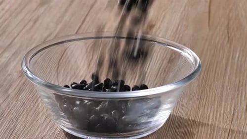 Filling Clear Bowl with Shiny, Dried Black Beans