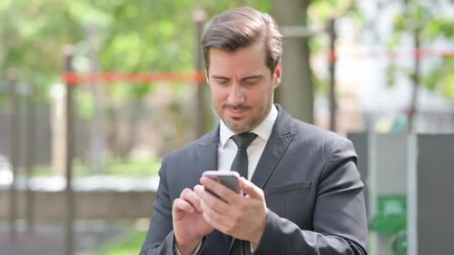 Dark Haired Adult Using Phone Outdoors