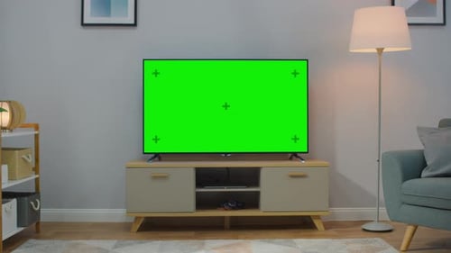 Zoom Out Shot of a TV with Horizontal Green Screen Mock Up. Cozy Living Room at Day Time with a Cha