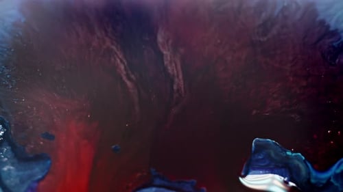 Abstract aerial view of red and blue ink diffusing in water, resembling a cosmic nebula