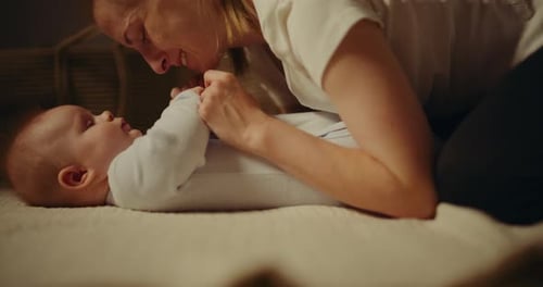 Woman Holding Infant on Bed in Home Interior