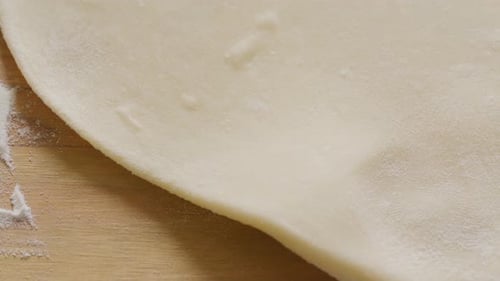 Flattening Dough with Rolling Pin on Wood Surface