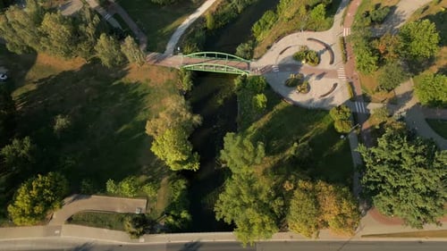 Drone shot reveals urban city park across beautiful river, Elk city gothic architecture buildings an