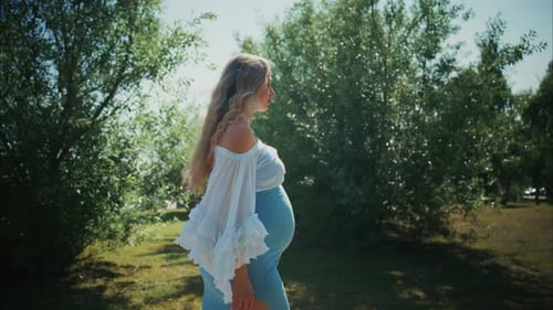 Pregnant Woman Walking in a Green Park