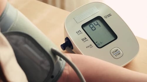 Weibliche Hand mit automatischem Tonometer zur Blutdruckmessung