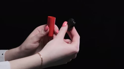 Red color vape pod system with replaceable cartridges in female hands isolated on black background.
