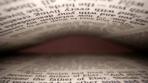 Slowly pulling lens out of a book at a words eye view of the pages, pages on both top & bottom of vi