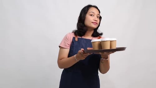 Young Woman Holding Coffees Waves and Smiles