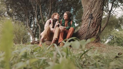 Romantic Couple Sitting by Tree in Forest