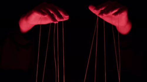 The Puppeteer Controls the Puppets in the Theater in Red Neon Light Closeup Managing People at Work