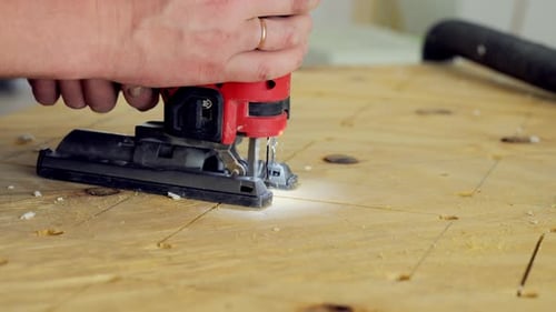 Person Using Jigsaw Power Tool The Worker is Holding the Jigsaw with Both Hands Guiding It Precisely