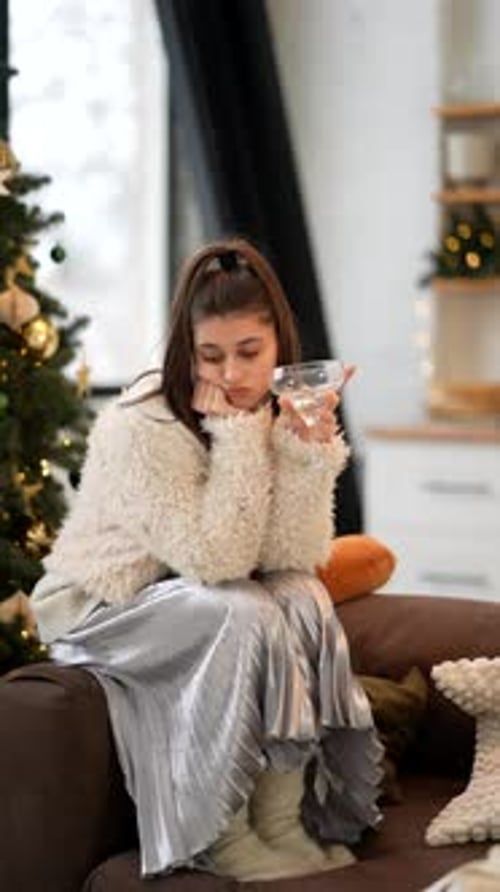 A Cozy Indoor Scene Featuring a Thoughtful Young Woman Who is Sitting Comfortably on a Couch