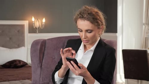 Busy Woman Standing in Hotel Room Typing on Mobile During Business Trip