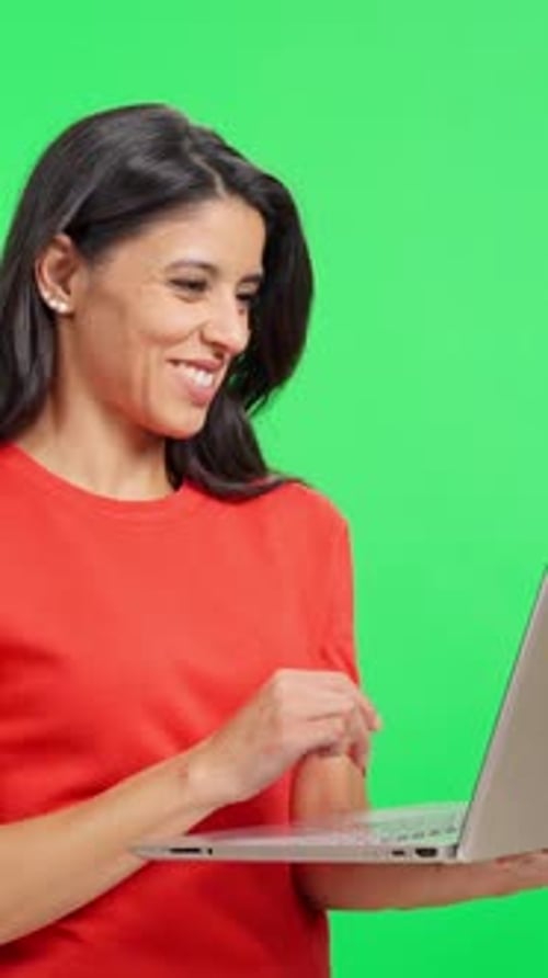 Woman working on laptop in front of greenscreen