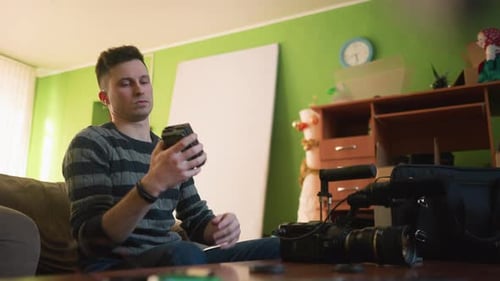 Studio Guy Sitting on Sofa in Home Studio Fixing Lighting
