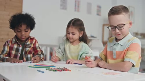 Children Drawing Pictures at a Table in Classroom