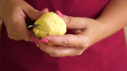 Hands Peeling and Cutting a Fresh Apple