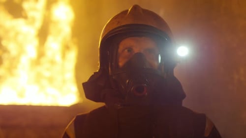 Foto de
retrato de um bravo bombeiro em pé em um prédio em chamas. Chamas abertas