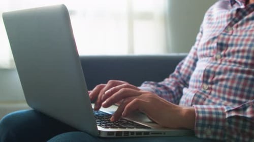 Man Typing on Laptop Keyboard in Home