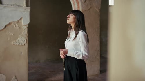 Woman Praying In Devotion With A Rosary In The Hands Inside A Church
