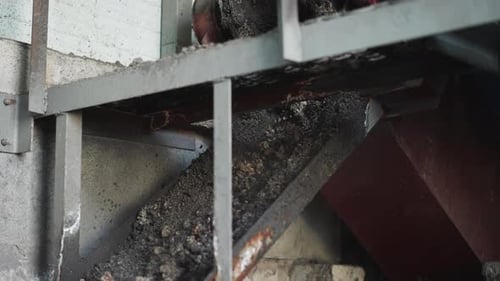 Kohle fließt aus dem Feeder im Lager von Industrieanlagen nach unten