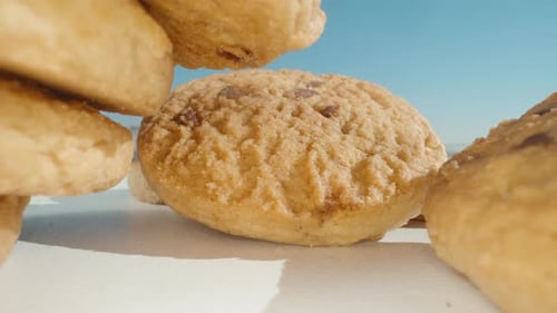 Round cookies with pieces of chocolate, on the table, I take one. Dolly slider close-up.