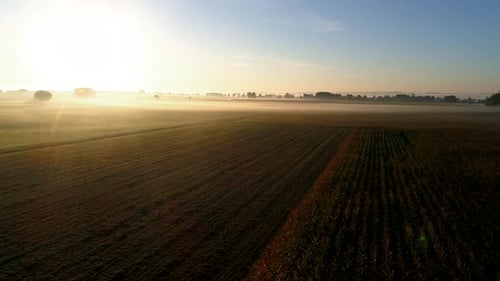 4K aerial slow motion flight at sunrise over foggy agricultural fields in germany