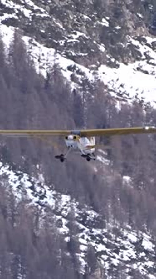 Bush airplane flying straight to camera with snow covered mountain