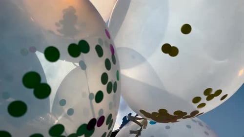 Confetti-Filled Balloons Floating Upward on a Sunny Day