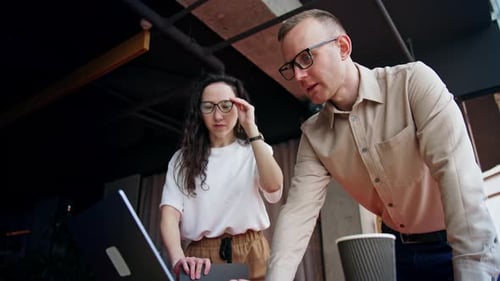 Office employees discussing the project on the laptop. Young people talk pointing at the screen,