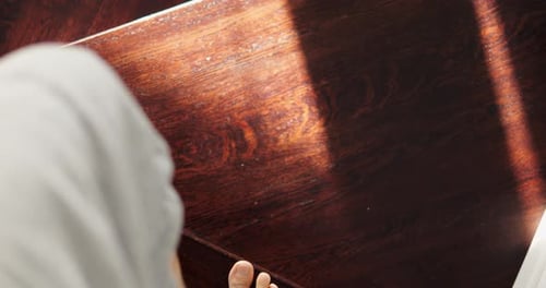 Young Man in Trousers Walks Down Wooden Spiral Steps Illuminated By Sunlight
