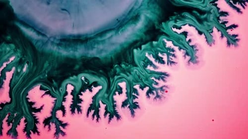 Abstract shot of vibrant green and pink liquids blending and swirling together