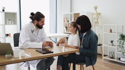 Doctor with Smiling Sick Girl and Mother in Medical Clinic