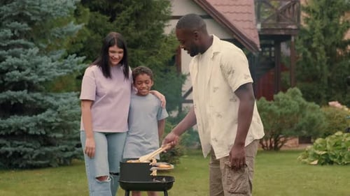 An African Dad Cooks Grill Vegetables for His Multiethnic Family