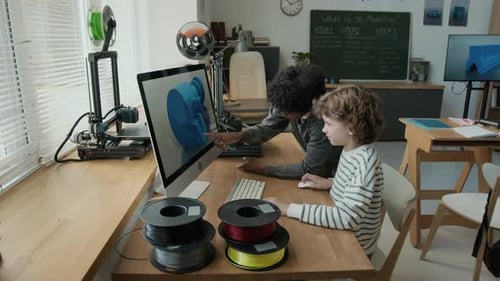 Dois meninos usando um computador para modelagem 3D durante a aula na escola