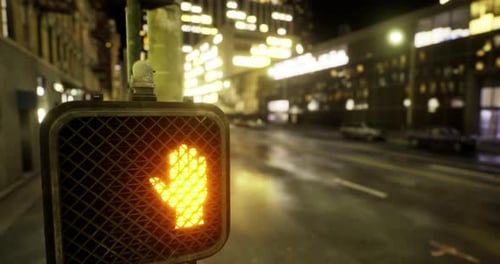 City Pedestrian Signal Displaying Stop Hand at Night in Urban Setting